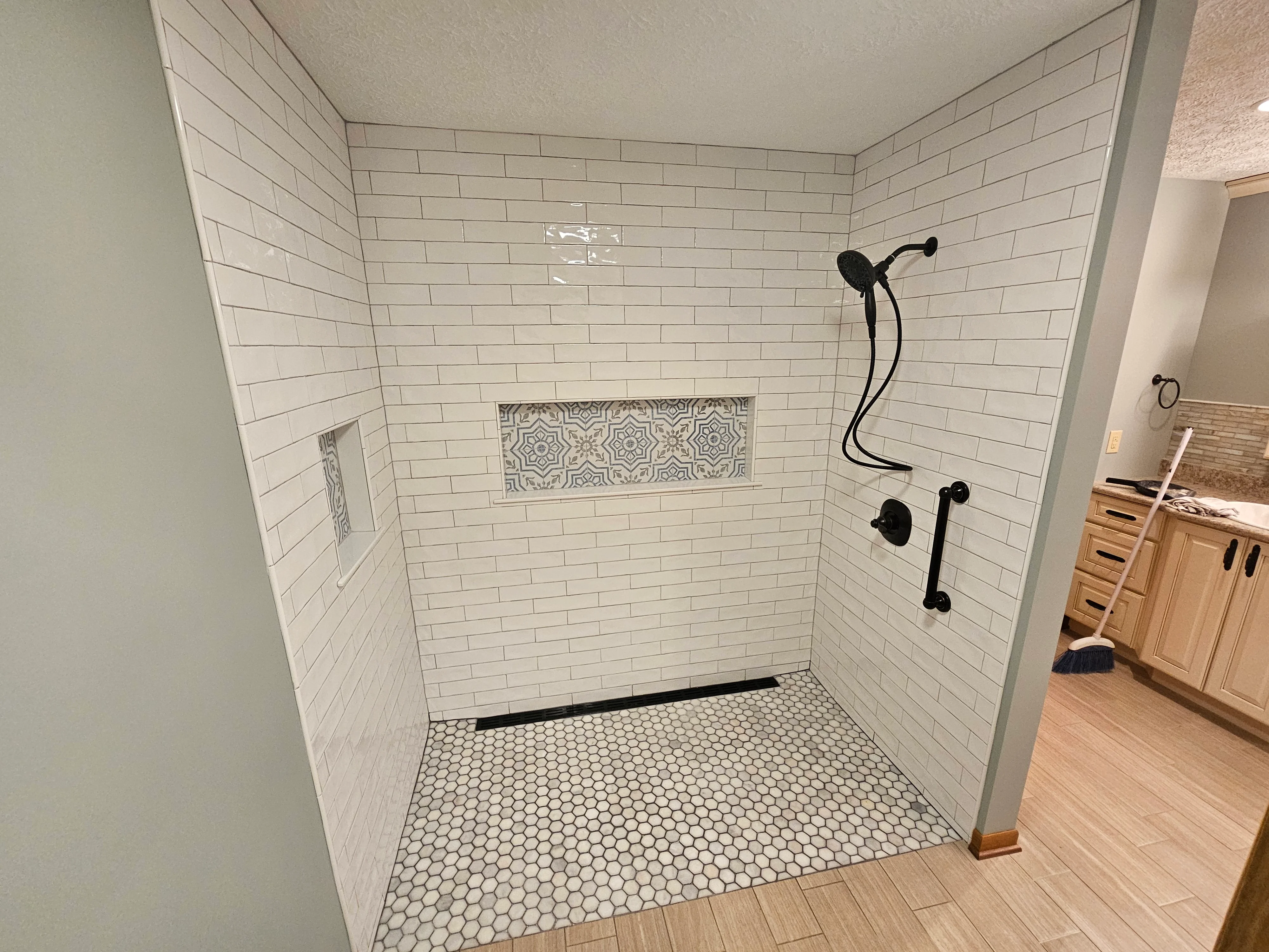 Shower with subway tile and black fixtures completed by Triple R Construction Inc.