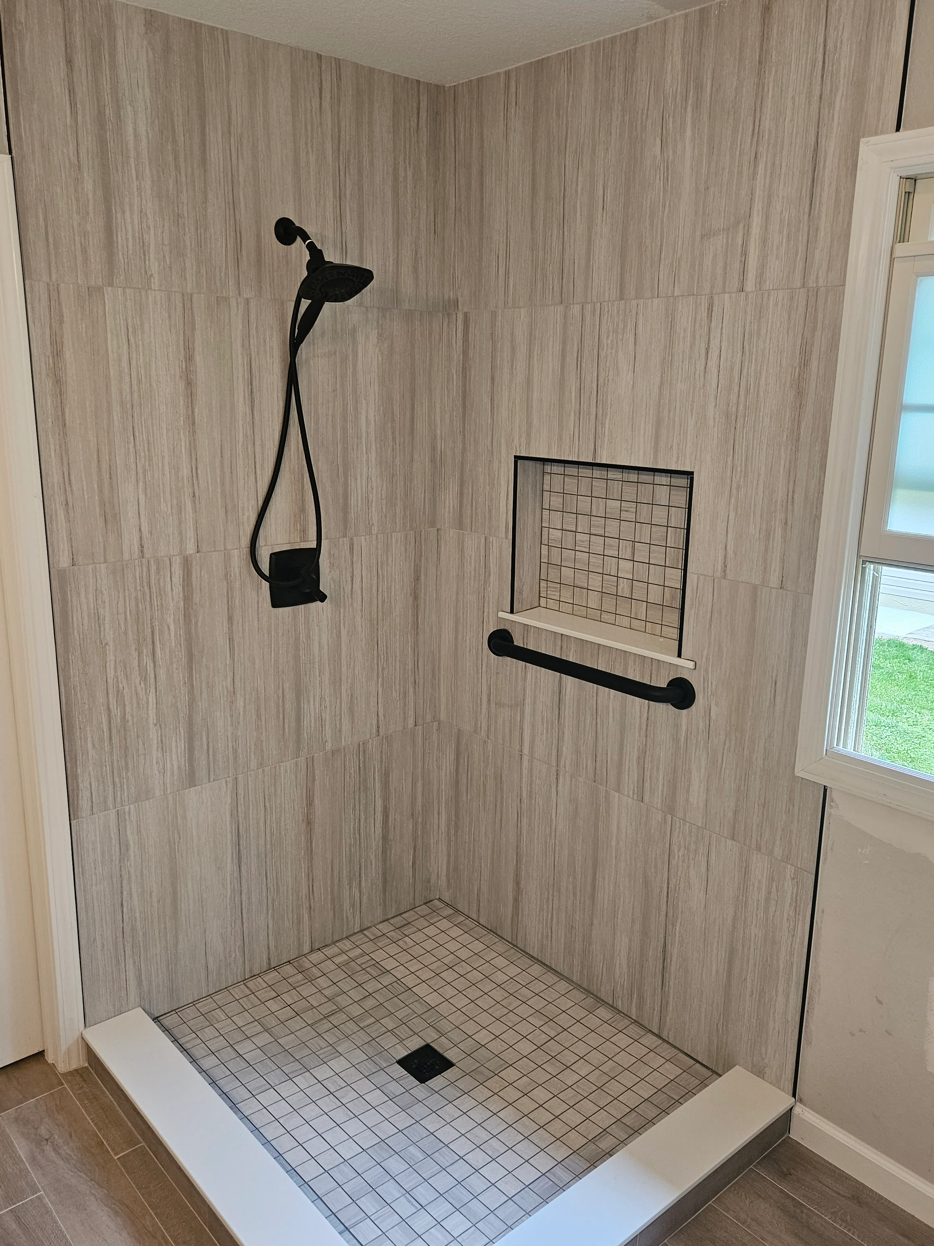 Shower with wood-grain tile and glass door completed by Triple R Construction Inc.